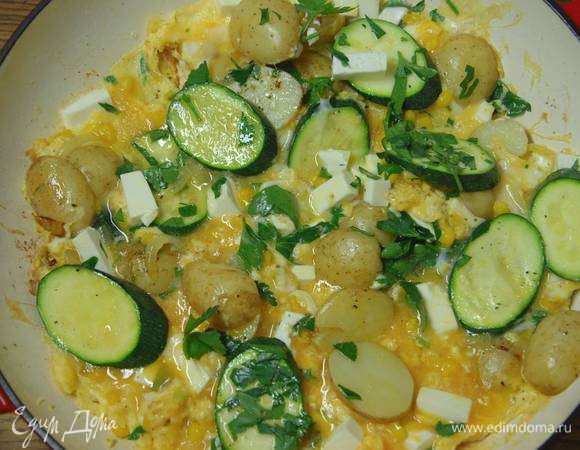 Яичную массу вылить в сковороду с обжаренными овощами, сверху разложить фету, посыпать петрушкой и готовить тортилью до той степени прожарки, которая вам по вкусу.