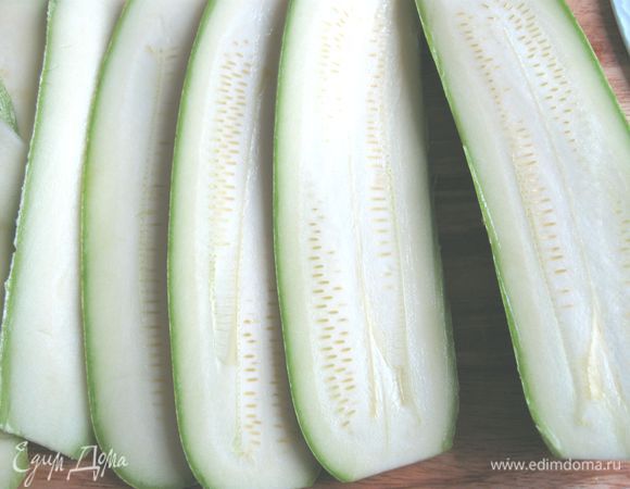 Духовку разогреть до 190°C.  Болгарский красный перец завернуть в фольгу, запечь в духовке в течение 30 минут. Молодые кабачки (не чистить) нарезать вдоль на тонкие пластинки, посолить. 