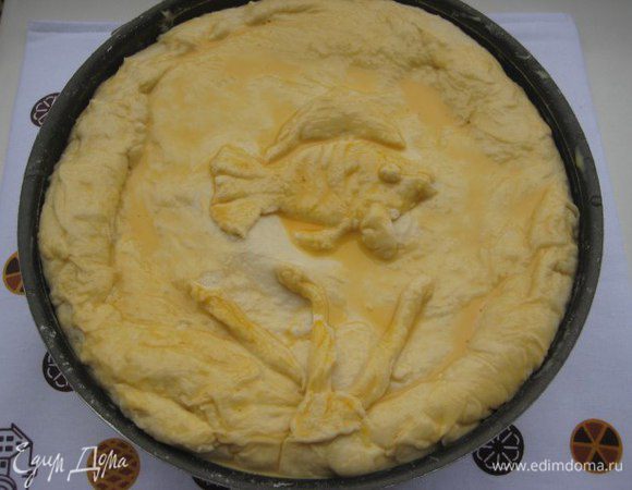 Из меньшей части сформировать верхушку пирога, защипать края пирога, украсить по желанию, у меня золотая рыбка. Яичный желток смешать с 1 ст. л воды, смазать яичной смесью пирог.