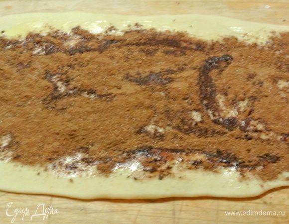 Для куличей я использовала 2 формочки: диаметром 14 см и 9 см. Тесто разделить на 2 неравные части: одну побольше, другую — меньше, так как формочки разного диаметра. От каждой части отщипнуть 1/4 часть теста на оформление верха, пока отложить. Тесто раскатать в пласт толщиной 5 мм. Кисточкой смазать растопленным сливочным маслом. Сверху посыпать смесью корицы, какао и сахара.