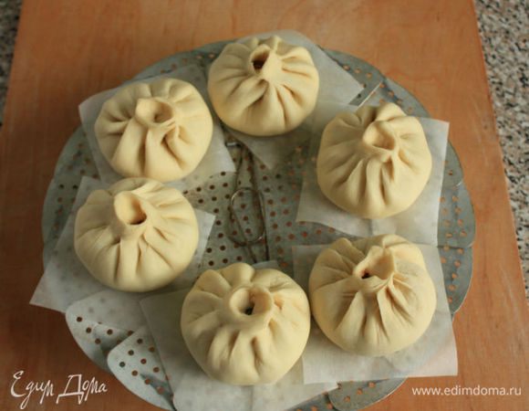 Нарежьте пергамент небольшими квадратиками, положите их под каждый пирожок на пароварку. Расстояние между баоцзы должно быть достаточное, т.к. они сильно увеличатся в объеме (на этом фото маленькое расстояние, я потом оставила 5 штук и кусочки пергамента нужны поменьше). В кастрюлю налейте кипяток так, чтобы он был ниже уровня пирожков минимум на 2 см, включите огонь. Поставьте пароварку в кастрюлю, накройте крышкой с отверстием и готовьте 15 минут. Очень важно после выключения огня не снимать крышку 5 минут! 