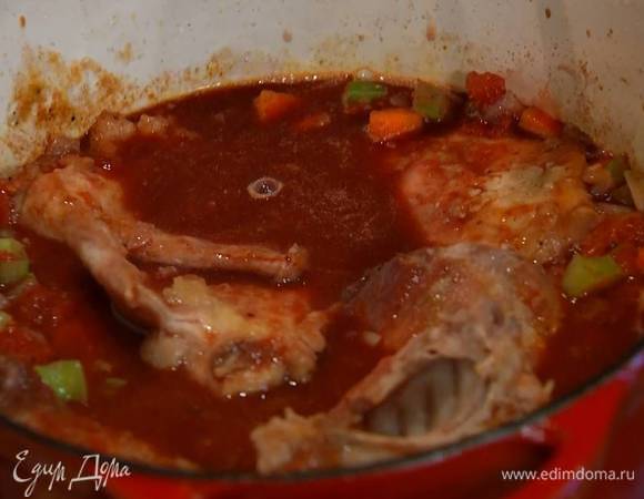 Выложить к овощам консервированные помидоры, влить 300 мл красного вина, все перемешать и довести до кипения, затем опустить в соус кусочки кролика, уменьшить огонь, накрыть крышкой и томить в течение часа.