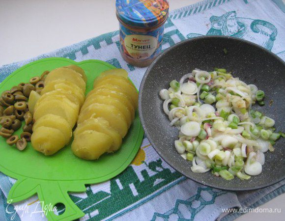 Лук нарезать колечками, обжарить на оливковом масле. Нарезать колечками картофель и оливки.