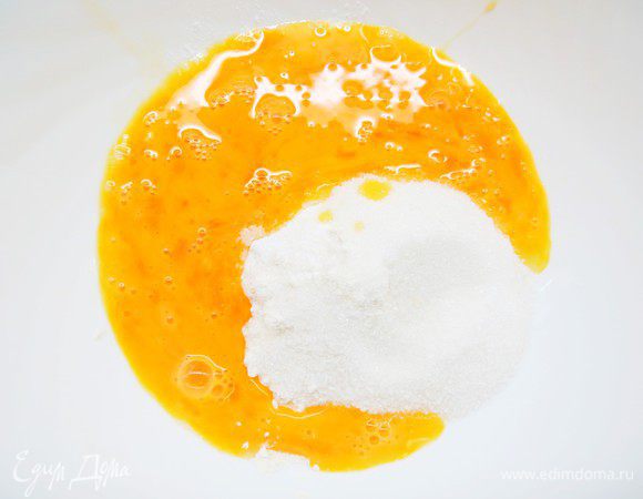 Два яйца слегка взбить венчиком и влить в смесь муки с сахаром.
