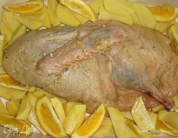 Утку выложить в противень с высокими бортами или в форму для запекания. Выложить по краям картофель и апельсины, полить все маринадом. Закрыть форму фольгой и поставить в разогретую до 200°С духовку на 1 час.