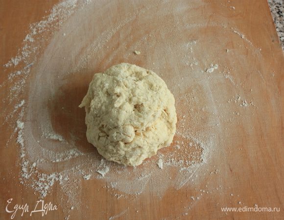Воду комнатной температуры соединить с растительным маслом и влить в муку. Все перемешать, собрать в шар и переложить на присыпанную мукой рабочую поверхность.