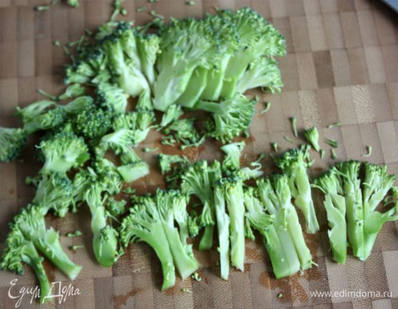 Вскипятить воду в чайнике. Брокколи помыть и разобрать на соцветия, крупные стебли тонко нарезать и сложить в жаропрочную посуду.