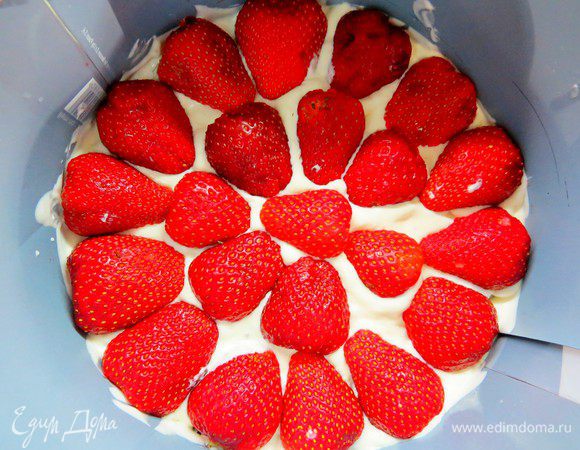 На пропитанный корж выливаем половину нашего мусса из белого шоколада и отправляем форму в холодильник для застывания. Я использую морозильную камеру, слои застывают минут за пять. Достаем форму, выкладываем равномерно клубнику и заливаем оставшимся муссом.