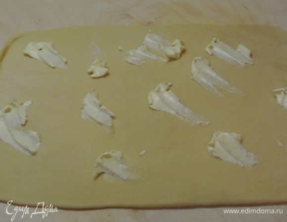 Одну часть теста раскатать в пласт толщиной 3 мм. Выложить половину рязмягченного масла.