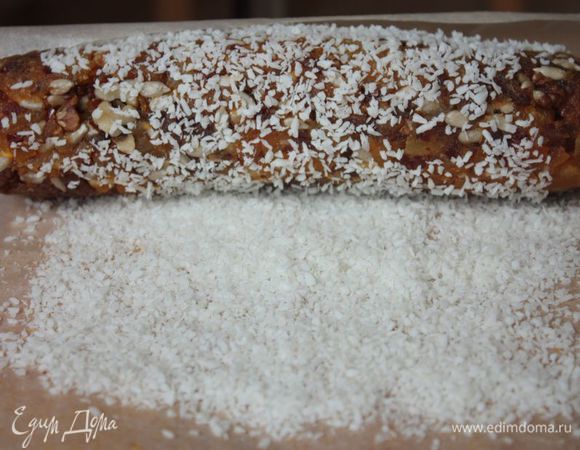 Обваляйте колбасу в кокосовой стружке и снова заверните в пергамент. И уберите в холодильник на 2,5-3 часа, чтобы она лучше схватилась. 