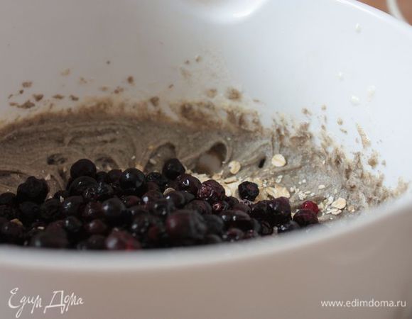 Влейте в тесто теплое молоко и снова взбейте до однородности. Добавьте смородину и овсяные хлопья.