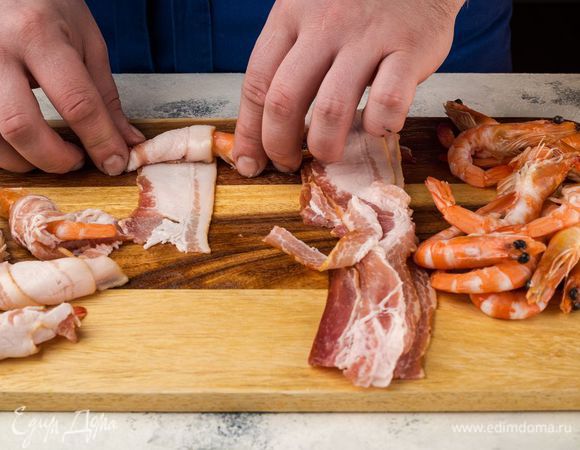 Бекон нарежьте тонкими полосками. Каждую креветку закрутите в бекон и скрепите зубочисткой.