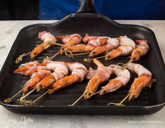 Гриль слегка смажьте оливковым маслом. Выложите на него креветки в беконе и пожарьте по 2 минуты с каждой стороны.
