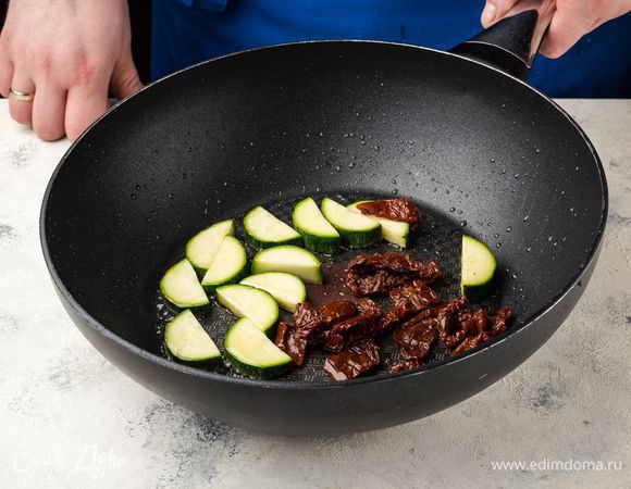 На оливковом масле поджарьте цукини и вяленые помидоры в течение 5 минут.