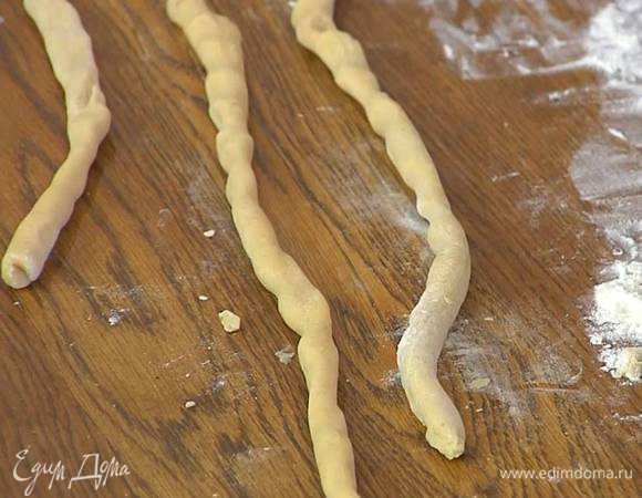 Рабочую поверхность присыпать оставшейся мукой и раскатать охлажденное тесто в тонкие колбаски.