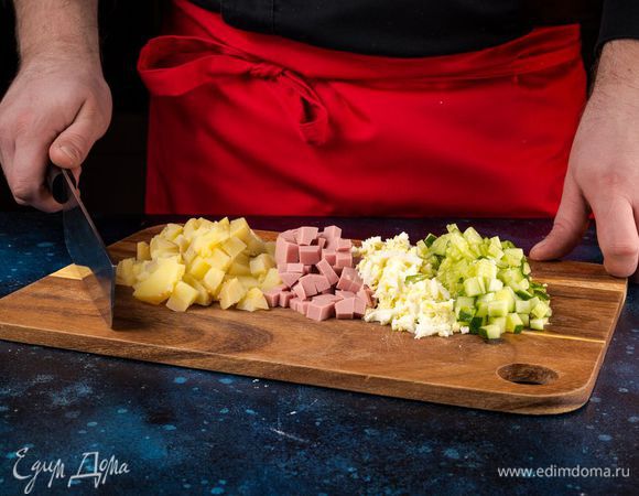 Нарежьте кубиками колбасу, очищенный картофель, очищенные яйца и огурцы.