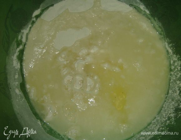 Влить теплую сыворотку и добавить яичный белок. Начать замешивать тесто ложкой. Затем влить подсолнечное масло и вымешивать тесто в течение 5-ти минут.