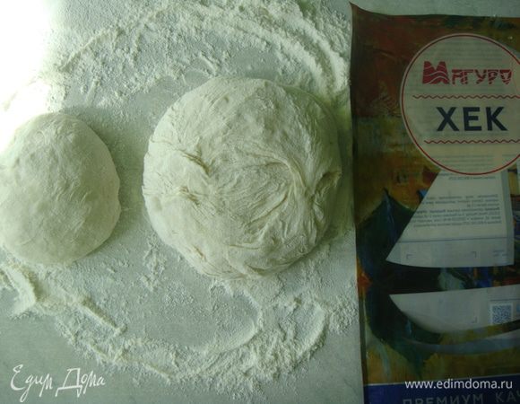 Стол присыпать мукой, выложить тесто и немного вымесить его. Разделить на две части, одну часть сделать поменьше другой.