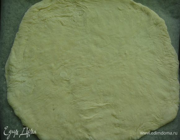 Противень застелить пергаментом. Большую часть теста раскатать в круг и перенести на противень.