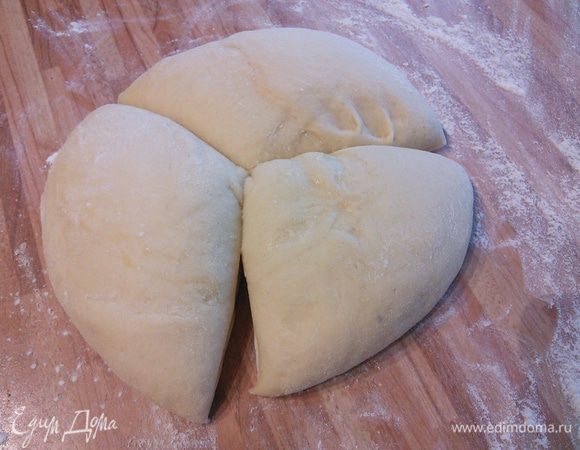 Тесто соберите в комок, затяните чашу пленкой и поставьте в теплое место на расстойку на час. Тесто увеличилось в размере в два раза. На посыпанной мукой поверхности разделите тесто на равные части. Из этого количества ингредиентов получается 3-4 лепешечки, зависит от тонкости раскатки теста. Скатать в шарики.