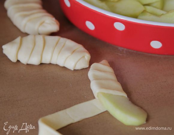 Яблоки очистить от кожуры, вырезать сердцевину, нарезать дольками. Обмотать каждую дольку полоской теста.