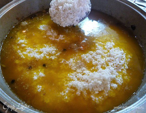 Перед засыпкой риса чеснок убираем, всыпаем рис и равномерно разравниваем его шумовкой. 