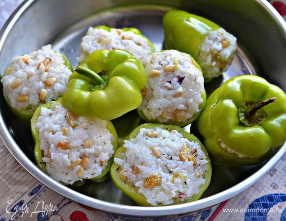 Перчики нафаршируйте начинкой, аккуратно утрамбовывая ее чайной ложкой. Сверху накройте крышками от верхушек перцев, плотно прижав к рисовой начинке. В сотейнике разогрейте оливковое масло, уложите перчики в один ряд, слегка поджарьте бока перцев в течение 3–5 мин. Затем поставьте перцы вертикально, влейте вино, закройте крышкой и готовьте на маленьком огне до готовности  в течение 25–30 мин.