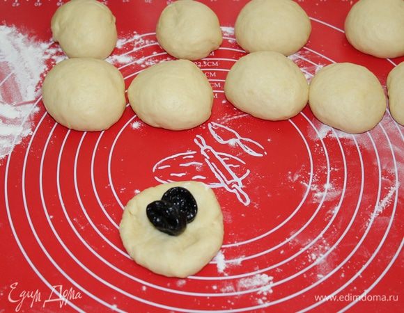 Когда тесто подойдет, обмять его, разделить на 10 кусочков. Из каждого кусочка теста внутрь положить по 2 чернослива или кураги. 