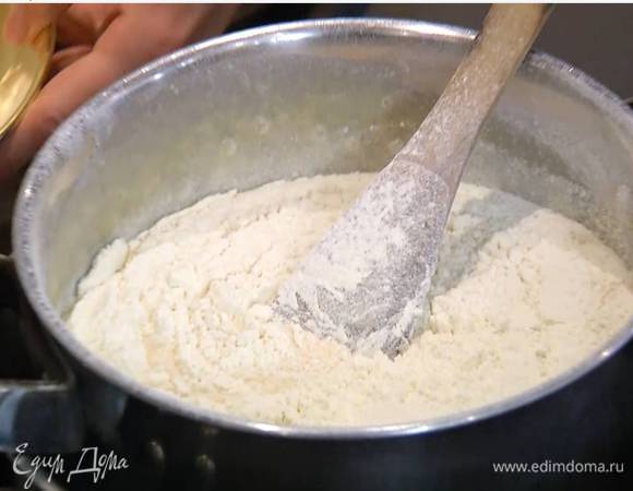 Снять кастрюлю с огня и, непрерывно перемешивая, добавить соду и уксус, а затем через сито всыпать 250 г муки и вымешать лопаткой.