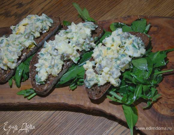 Руколу и шпинат посолить, полить оставшимся оливковым маслом и лимонным соком, перемешать и выложить на тарелку или деревянную доску, сверху поместить бутерброды с салатом.