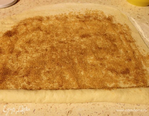 Смешать корицу с коричневым сахаром. Тесто разделить на две части, одну часть раскатать в пласт, толщиной 3-4 мм, распределить по тесту половину корицы с сахаром. Скатать плотно в рулет.
