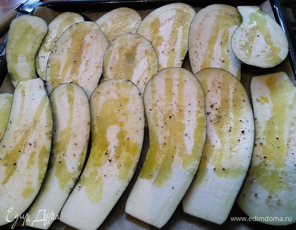 Нут заранее отварить или использовать консервированный. Для начала нужно поставить запекаться баклажаны. Их можно обжарить на сковороде в масле, но я предпочитаю именно запекание. Баклажаны нужно нарезать тонкими ломтиками, выложить на противень, посолить, поперчить и сбрызнуть оливковым маслом. 