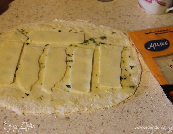 Тесто разделить на две части, каждую раскатать в прямоугольник толщиной 3–5 мм. Обильно смазать начинкой из масла. Сверху выложить сыр.
