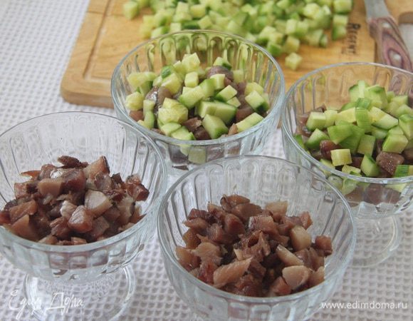 На слой риса выложить сельдь, затем огурчики.