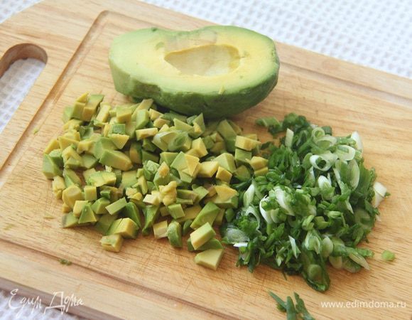 Авокадо так же нарезать кубиком, сбрызнуть соком лимона, чтобы не потемнело. Выложить слоем на яблочный слой. Зеленый лук нарезать мелко, наискосок.