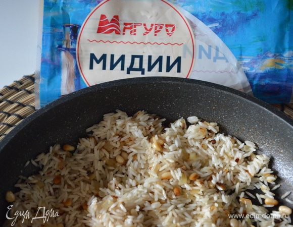 С риса слить воду, добавить рис к луку и орешкам, жарить еще 2-3 минуты.