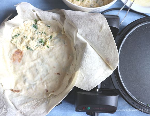 Сверху положить лист лаваша, вырезанный ножницами в форме круга. Затем, смазать масляно-йогуртовой смесью. Снова — начинка. И так продолжать, пока не используется вся начинка. 
