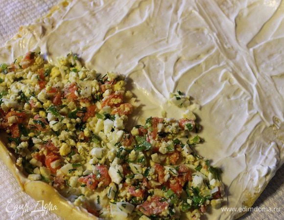 Сверху выложить начинку, разровнять ее и свернуть рулет по короткой стороне.
