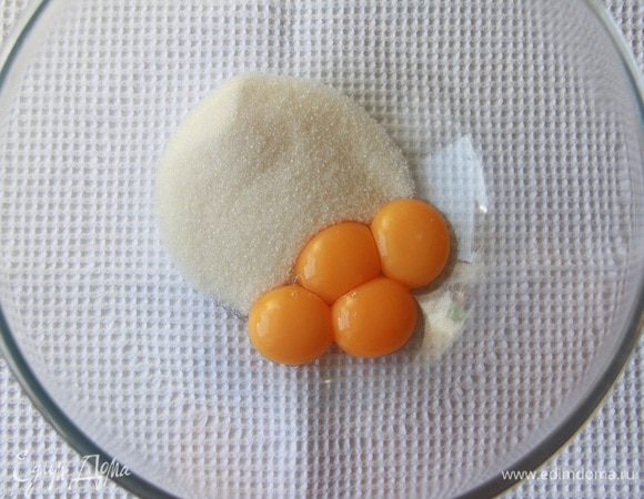 Желтки отделить от белков и соединить с половиной стакана сахара.