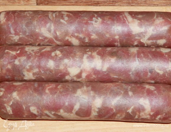 Далее замачиваем коллагеновую оболочку в воде на 10-15 минут, чтобы придать ей эластичность. Наполняем оболочку любым приемлемым способом. Я в этот раз делала это при помощи вилки: выкладывала порциями, а затем просто поджимала фаршемассу,  скручивая оболочку. В конце уплотнила массу, поджав ее довольно туго, и завязала шнур. Из предложенного количества у меня получилось три таких небольших батончика ветчины. Отправляем их в холодильник для осадки на 12 часов.