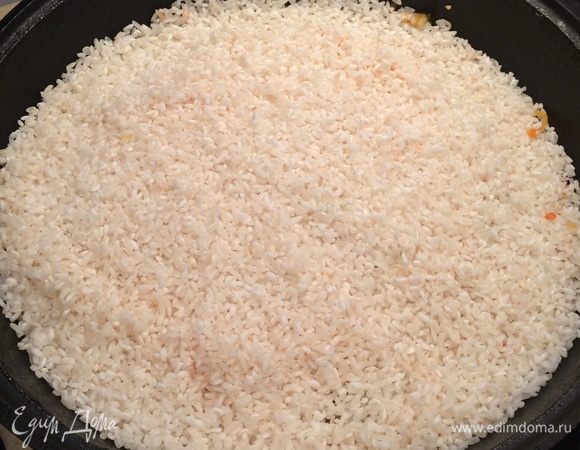 Через 40 минут на протушенное мясо и овощи выложить ровным слоем подсохший рис, залить кипятком (в кипяток нужно предварительно добавить еще 1 ст. л. соли) так, чтобы уровень воды был на 1 см выше уровня риса. После этого рис не трогать и ни в коем случае не перемешивать. Довести до кипения, плотно закрыть крышкой и варить плов на медленном огне около 40 минут. Вся вода должна полностью впитаться в рис.