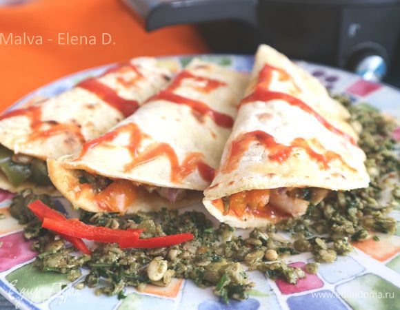 Начинка. Болгарский перец (у меня здесь разноцветный — желтый, оранжевый, зеленый, красный, по половинке перца каждого цвета) завернуть в фольгу и запечь в предварительно разогретой до 200°C духовке, время — 30 минут. Одновременно с перцем следует запечь головку чеснока, разрезанную поперек и завернутую в фольгу. Варено-мороженые небольшие по размеру креветки разморозить и прогреть на водяной бане, очистить. Смешать креветки с остывшим и порезанным соломкой болгарским перцем и зубчиками очищенного чеснока. Добавить очищенный от шелухи красный лук, порезанный тонкими полукольцами. Посолить, поперчить. Если в смеси излишнее количество жидкости — положите начинку на время на дуршлаг. Тортильи перегнуть ее пополам. Можно украсить песто и томатным соусом.