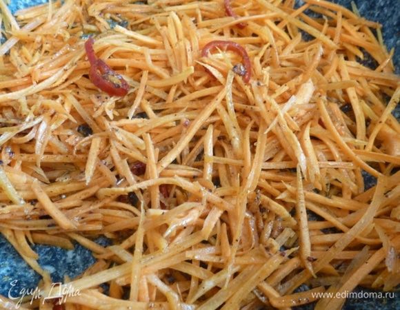 Разогреем сковороду, всыплем приправу для острых закусок, перец чили и немного прогреем. Кладем морковь и готовим ее 1 минуту. Важно, чтобы морковь осталась хрустящей.