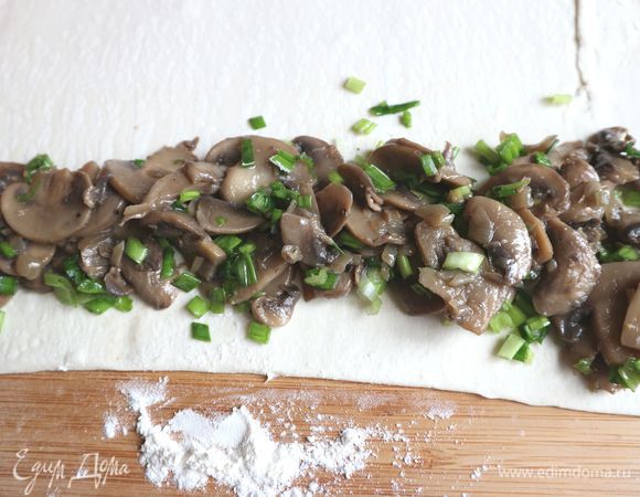 Часть теста тонко раскатать на присыпанной мукой поверхности, по ленте из теста расположить грибную начинку, можно ее немного присыпать мукой, защипнуть края, положить тесто с начинкой защипом вниз, свернуть улиткой. Не закручивайте тесто несколько раз в рулет, ограничьтесь максимально пол-оборотом. А то тесто не пропечется. Это будет «домик» улитки.