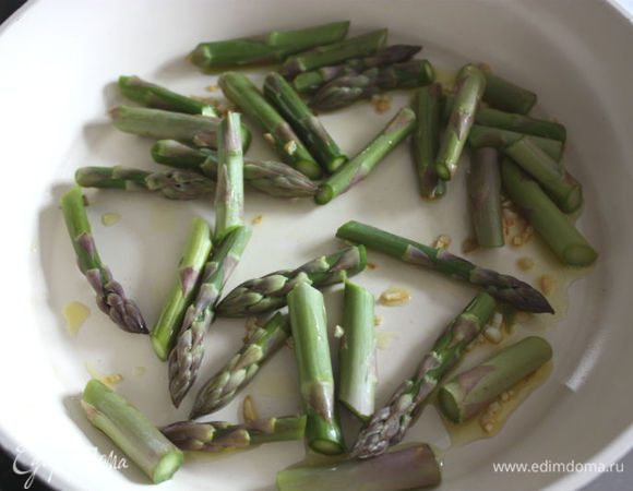Оливковое масло нагреть в глубокой сковороде, всыпать рубленый чеснок. Обжарить его до прозрачности. Добавить к чесноку сливочное масло и спаржу, накрыть крышкой и готовить 5 минут.