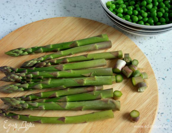 Замороженный горошек залить кипятком на 10 минут, затем воду слить.
Спаржу вымыть, удалить кончики и порезать побеги на 3 части.