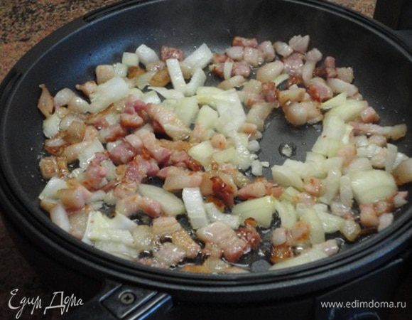 В глубокой сковороде на максимальном нагреве (выставляем на 5, а таймер на 10 минут — это на приготовление всей начинки) обжариваем бекон. Когда жир вытопится, добавляем лук, жарим до золотистости.