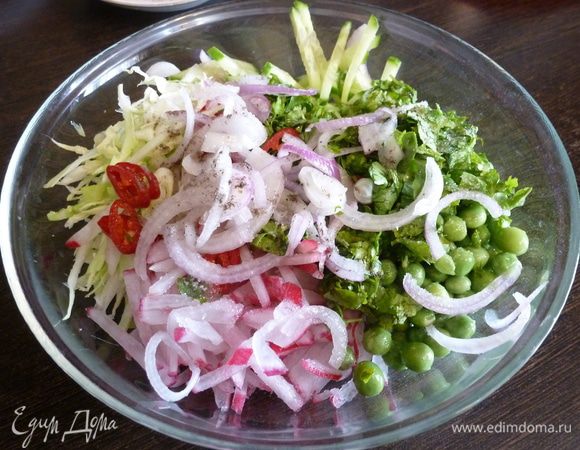 Нарежем редиску и огурец соломкой, тонко нашинкуем молодую капусту. Соединим вместе, добавим горошек, лук, перец чили. Посолим и поперчим.