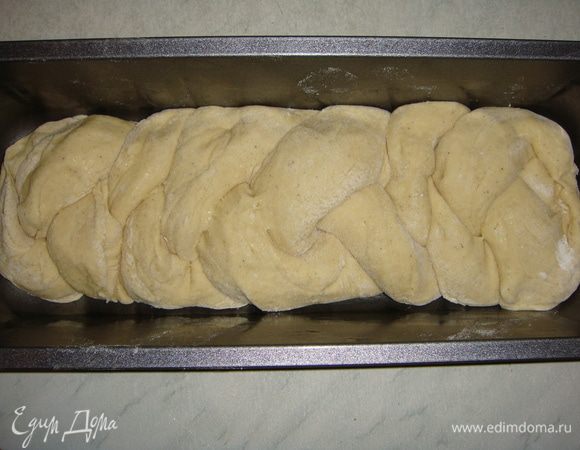 Форму для выпечки смазать подсолнечным маслом. Тесто разделить на 3 части, скатать колбаски и заплести косу. Переложить ее в форму, накрыть пищевой пленкой и поставить в теплое место на 40 минут.