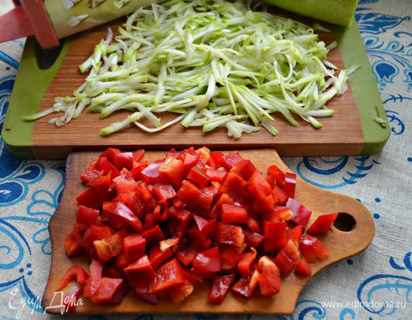 Для начинки помойте и натрите на крупной терке молодой кабачок. Два небольших перца также помойте и нарежьте небольшими кубиками.
